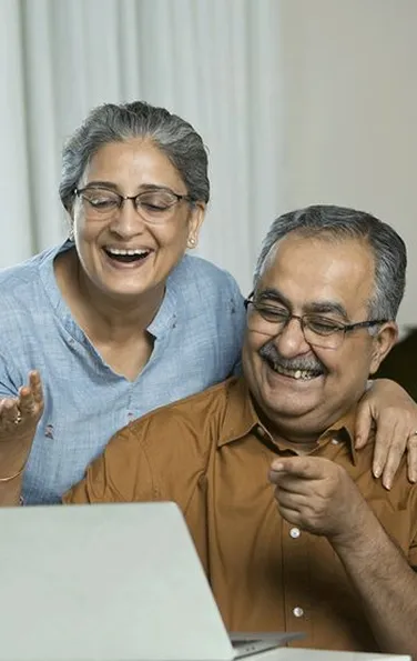 An older man smiling while using a laptop